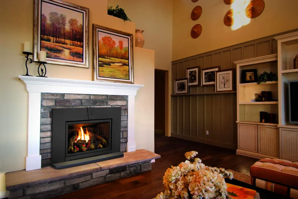 Insert au gaz Enviro E25, créant une ambiance chaleureuse dans un foyer en pierres décoratives avec un manteau de foyer blanc classique.