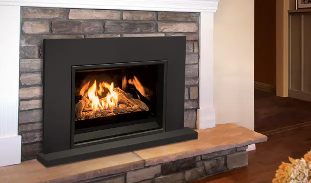 Vue détaillée de l'insert au gaz Enviro E30 avec une façade décorative à grille, ajoutant une touche de finition à un foyer en pierres.
