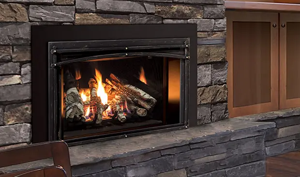 Gros plan sur la façade arquée de style traditionnel de l'insert au gaz Enviro E33, installé sur un âtre en pierres empilées.