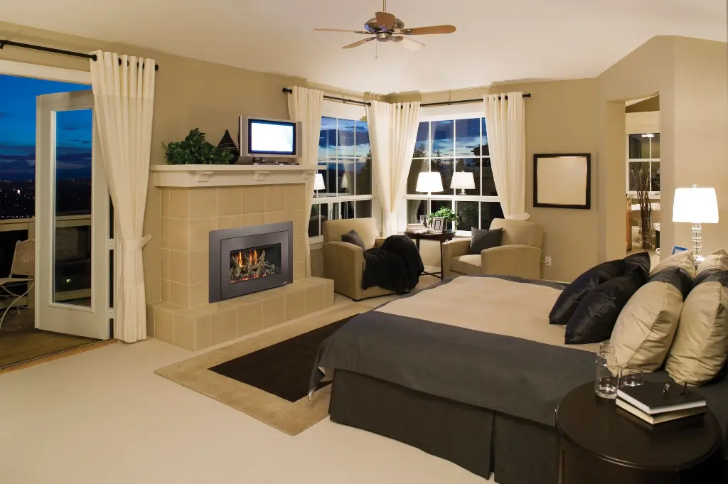 Ambiance luxueuse dans une chambre des maîtres avec l'insert au gaz 32 DVS, installé dans un manteau de foyer moderne avec vue sur la ville.