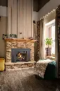 Ambiance de chalet scandinave avec le foyer au gaz 430 Deluxe, mis en valeur par un mur de lattes de bois verticales et un manteau en pierres pâles.