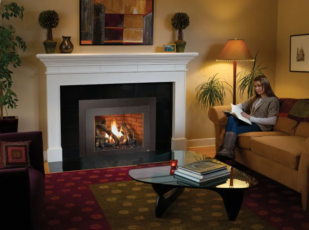 Coin lecture confortable et élégant avec le foyer au gaz 616 Deluxe, intégré dans un manteau de foyer blanc sur un contour en granite noir.