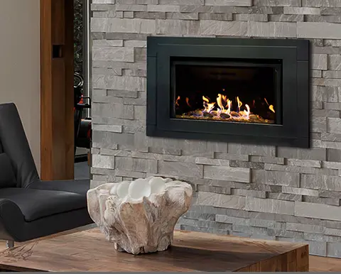 Grand insert au gaz de Savannah, créant un point focal moderne et texturé dans un mur d'accent en pierres décoratives grises.