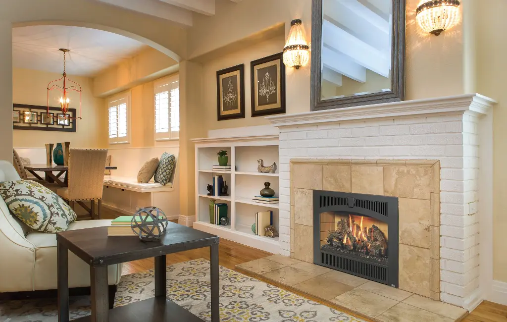 Foyer au gaz 564 TV 35K avec façade arquée, s'intégrant à un foyer en briques peintes en blanc et un contour en tuiles de céramique.