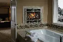 Créez une ambiance de spa à la maison avec le foyer au gaz 564 TV 35K et sa façade de style "forge", installé au-dessus d'un bain tourbillon.