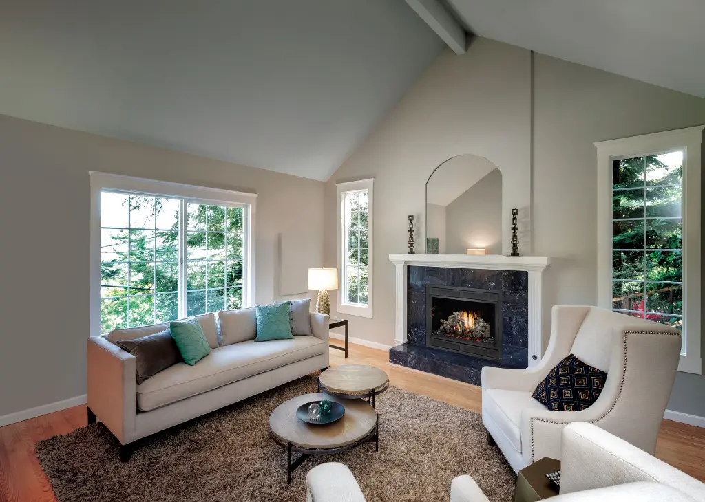 Look élégant et aéré dans un salon avec plafond cathédrale, mettant en valeur le foyer au gaz 864 TRV 31K dans un contour de marbre noir poli.