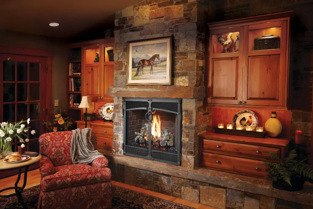 Coin détente rustique et intime avec le foyer au gaz 864 TV 40K et sa façade à portes, entouré de meubles encastrés en bois et d'un mur de pierres.
