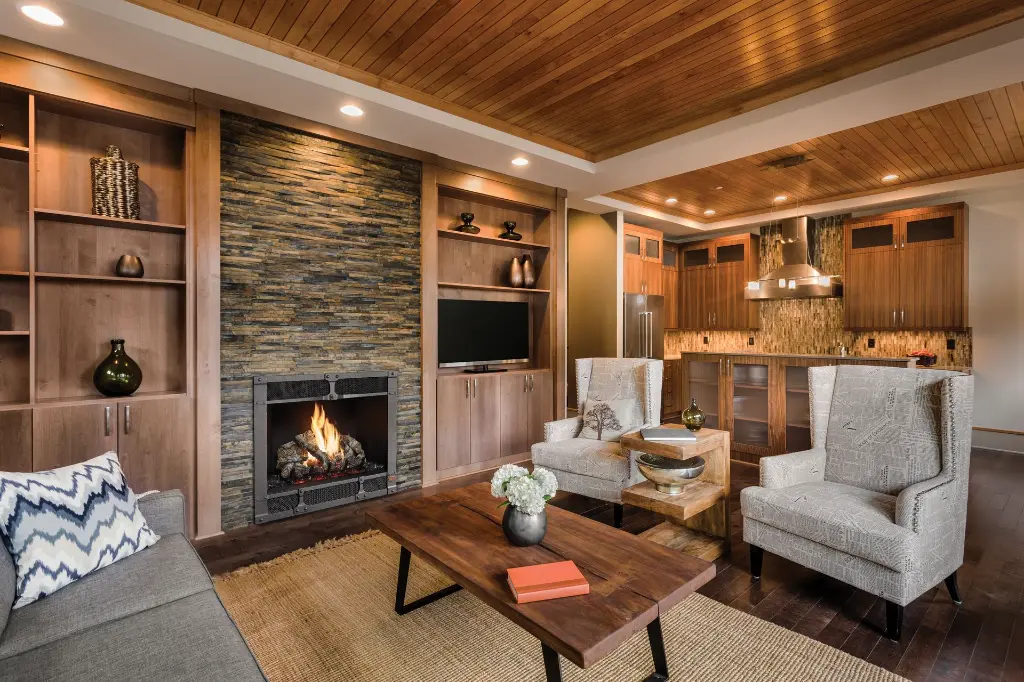 Design contemporain avec le foyer au gaz 864 TV 40K, encastré dans un mur d'accent en pierres modernes et flanqué de bibliothèques sur mesure.