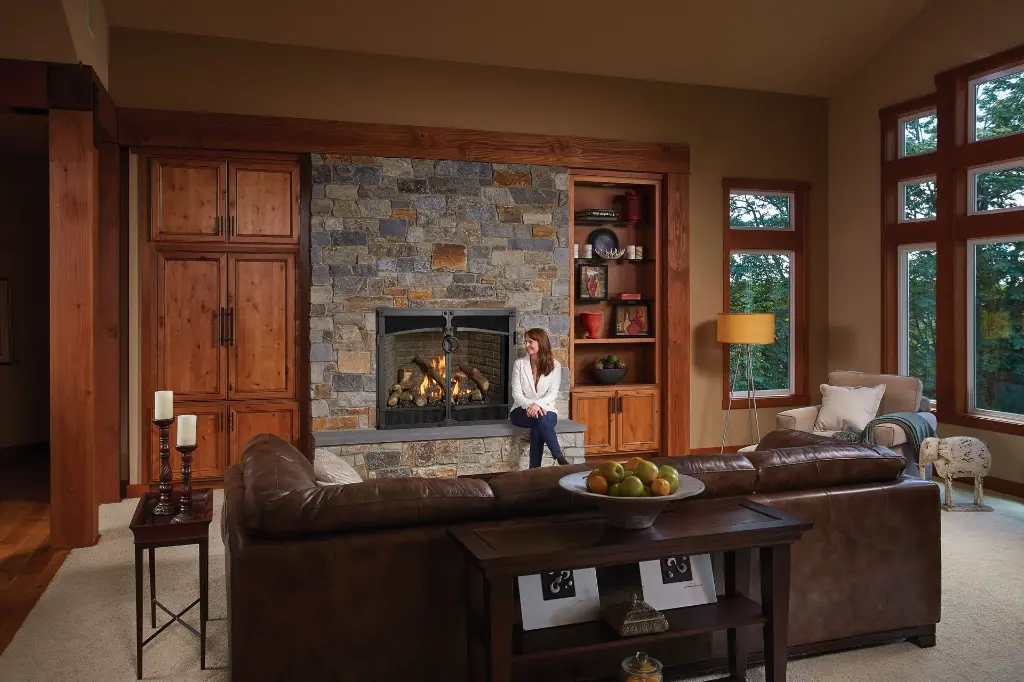 Gros plan sur la façade décorative arquée du foyer au gaz 4237 Ember-Glo, complétant un foyer en pierres de style rustique.