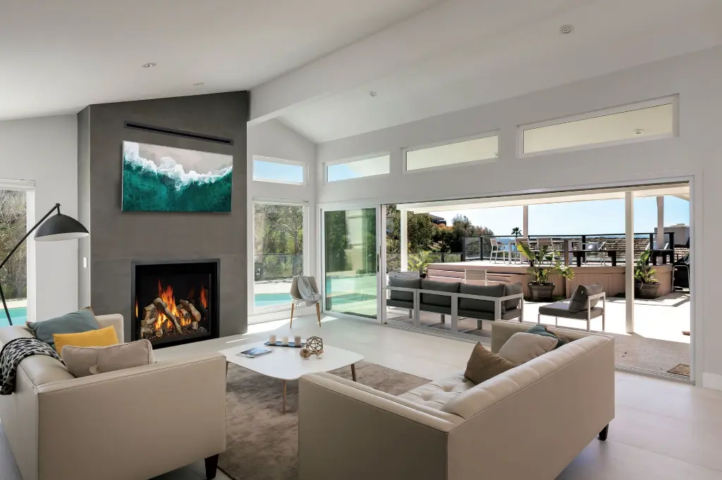 Design intérieur-extérieur moderne avec le foyer au gaz 4237 Ember-Glo installé sous une télévision dans un mur de foyer gris épuré.