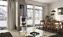 Poêle au gaz Jotul GF 370 noir mat sur piédestal, créant une ambiance chaleureuse dans un décor scandinave avec vue sur un paysage d'hiver.