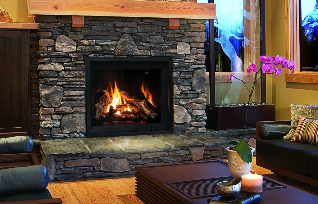 Grand foyer au gaz Enviro G42, créant une ambiance de chalet rustique dans une cheminée en pierres des champs avec un manteau en bois brut.