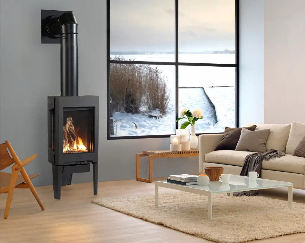 Poêle au gaz Jotul GF 160 noir mat sur pattes, apportant une chaleur confortable à un salon au design minimaliste avec une vue sur un lac gelé en hiver.