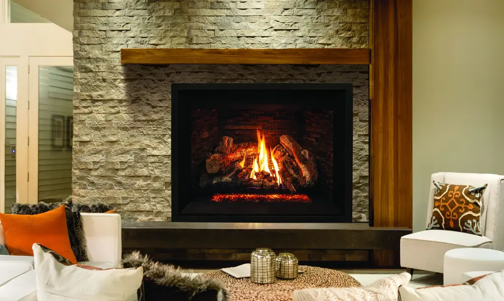 Ambiance de chalet moderne avec le grand foyer au gaz Enviro G50, installé dans un mur de pierres décoratives pâles avec un manteau de poutre en bois.