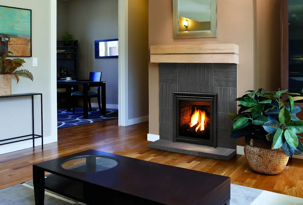 Look moderne avec le foyer au gaz Enviro Q1, encastré dans un manteau de foyer en tuiles de céramique foncées et surmonté d'une tablette en bois clair.