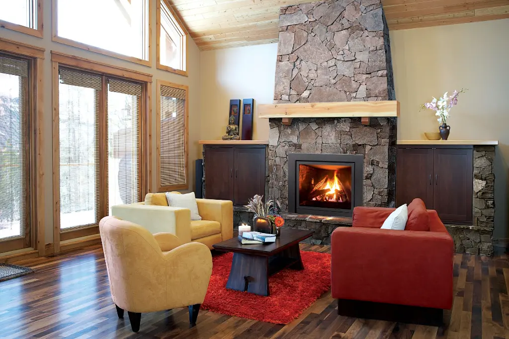 Foyer au gaz Enviro Q2, pièce maîtresse d'un chalet moderne avec une cheminée en pierres des champs et un plafond cathédrale en bois.