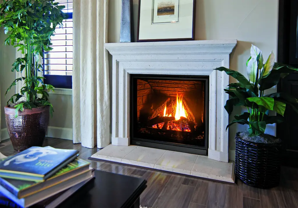 Élégance intemporelle avec le grand foyer au gaz Enviro Q3, encastré dans un manteau de foyer en pierre sculptée de style classique.