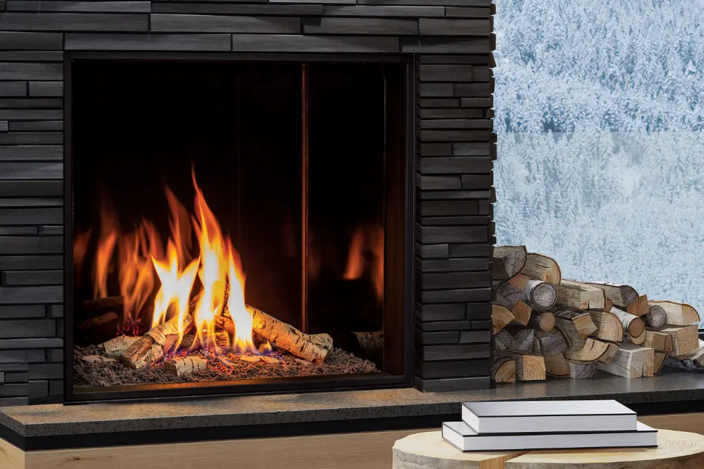 Vue rapprochée du foyer au gaz Urbana U33 avec ses bûches de bouleau, installé dans un contour de pierres modernes noires.