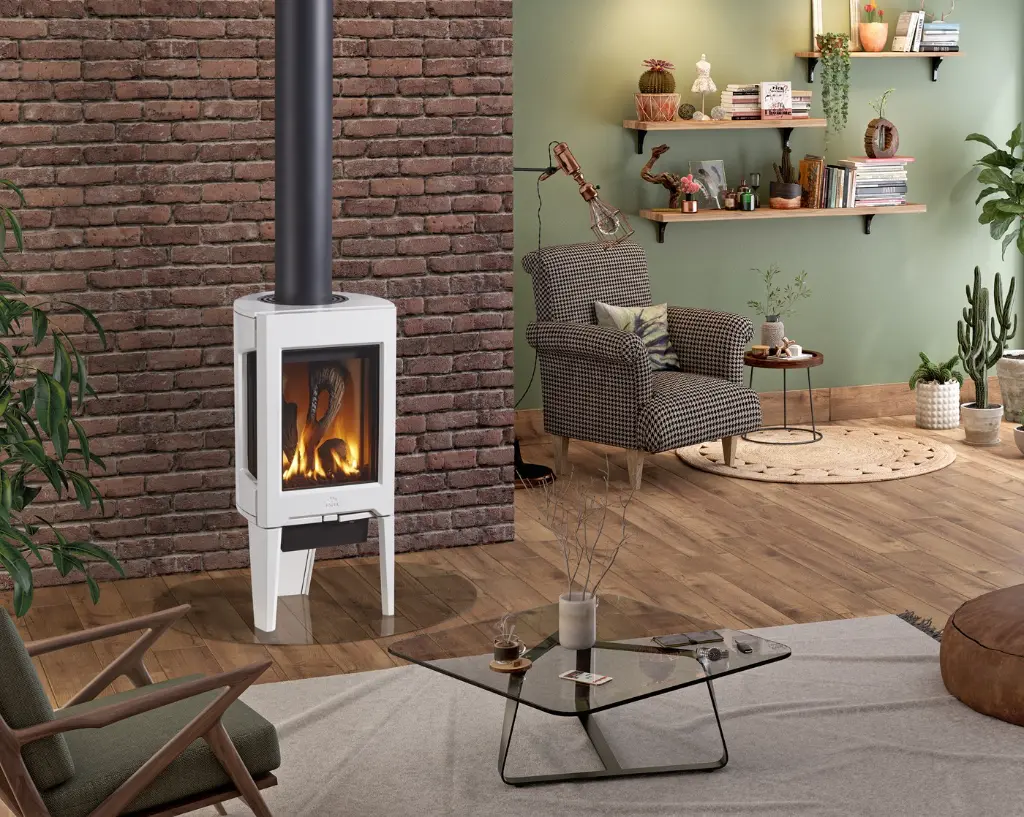 Poêle au gaz Jotul GF 160 blanc émaillé sur pattes, créant un coin lecture chaleureux devant un mur de brique dans un salon au style éclectique.