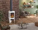 Poêle au gaz Jotul GF 160 blanc émaillé sur pattes, créant un coin lecture chaleureux devant un mur de brique dans un salon au style éclectique.