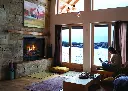Ambiance de chalet moderne avec le foyer au gaz RZ41 d'Enviro, installé dans une cheminée en pierres décoratives avec une vue sur un paysage d'hiver.