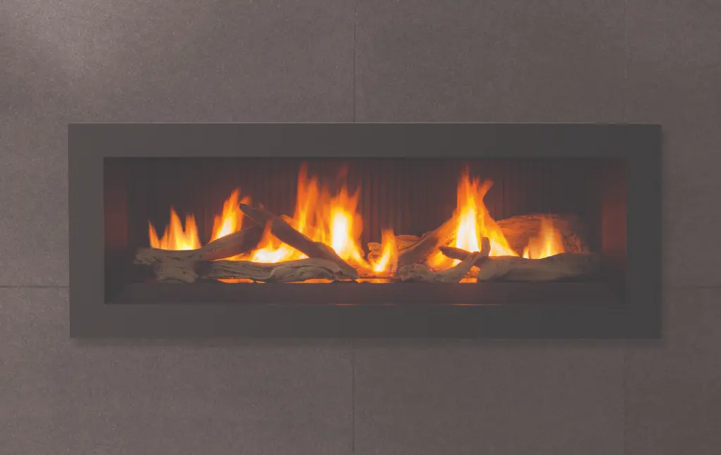Gros plan sur le jeu de bûches traditionnelles et la flamme panoramique du foyer au gaz linéaire Enviro C44 sur un fond de panneaux cannelés.