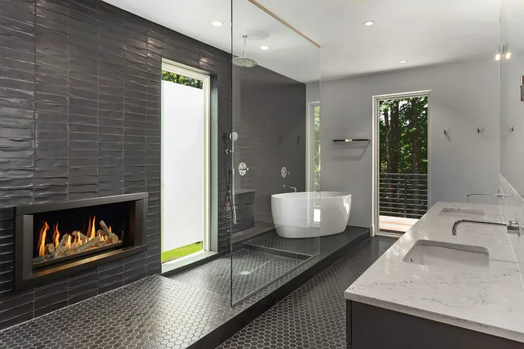 Créez une salle de bain de style spa avec le foyer au gaz linéaire 3615 HO, encastré dans un mur de tuiles de céramique foncées près d'une douche à l'italienne.