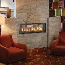Ambiance feutrée avec le foyer au gaz double face 4415 HO See-Thru, intégré dans un mur de tuiles de pierres pâles entre deux coins salon.