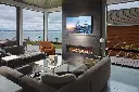 Vue imprenable sur la mer depuis un salon de luxe avec le foyer au gaz linéaire 6015 HO, installé sous une télévision dans un mur épuré.