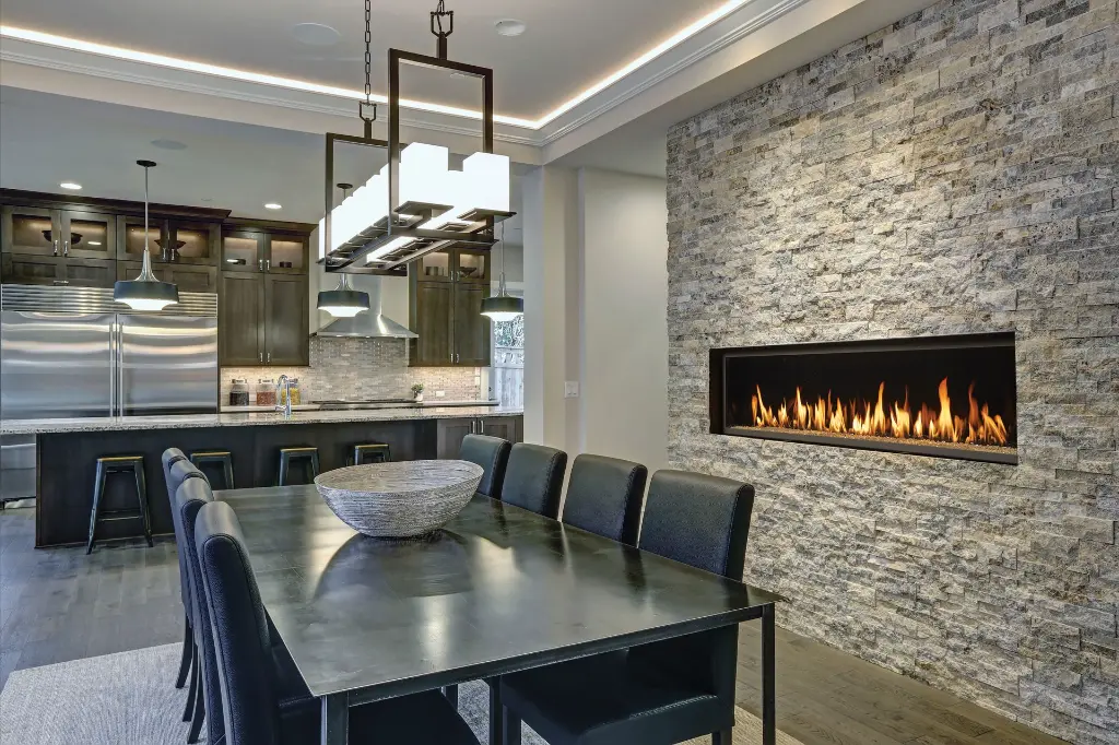 Ambiance sophistiquée dans une salle à manger avec un mur de pierres décoratives pâles, mettant en valeur le foyer au gaz panoramique 6015 HO.