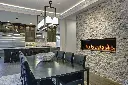 Ambiance sophistiquée dans une salle à manger avec un mur de pierres décoratives pâles, mettant en valeur le foyer au gaz panoramique 6015 HO.