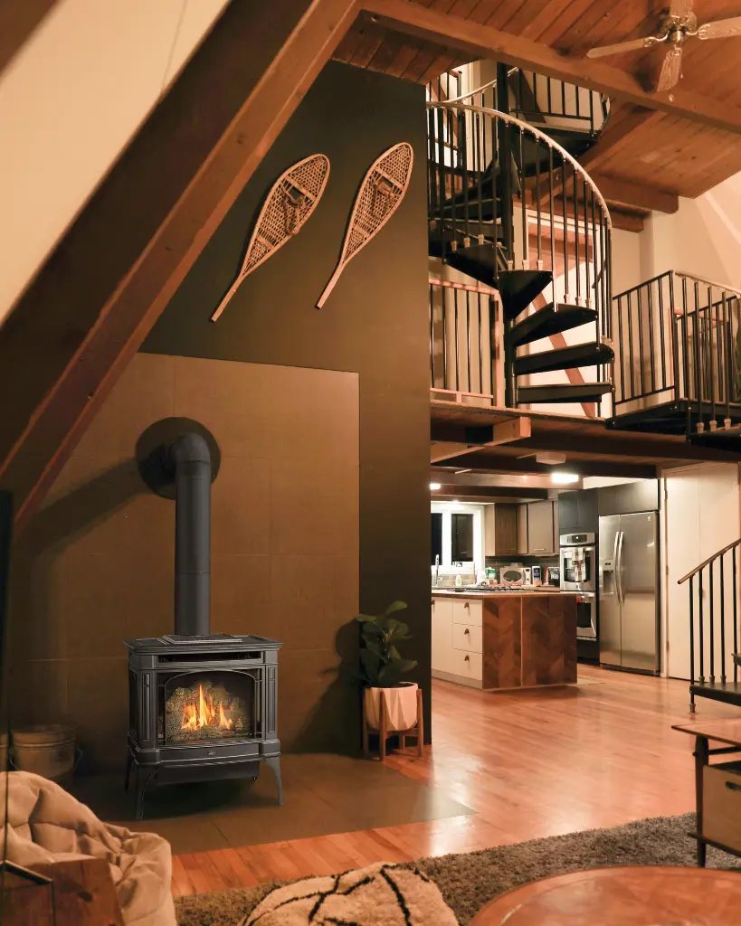 Style loft industriel chic avec un poêle à gaz Berkshire de Lopi, complétant un décor avec un escalier en colimaçon et des poutres de bois.