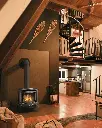 Style loft industriel chic avec un poêle à gaz Berkshire de Lopi, complétant un décor avec un escalier en colimaçon et des poutres de bois.