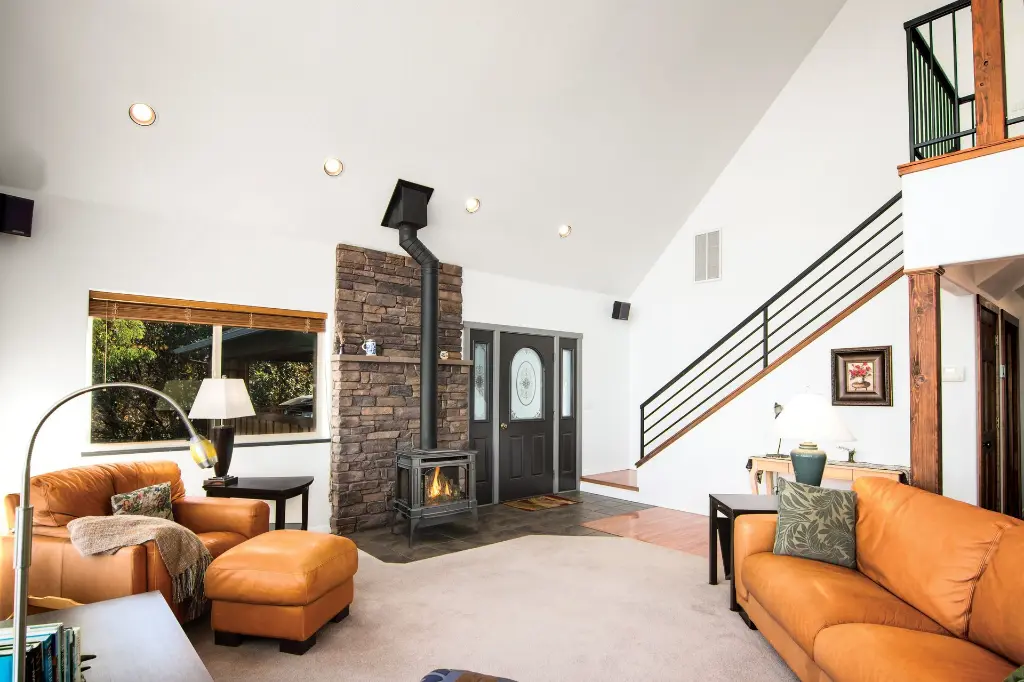 Poêle à gaz Berkshire de Lopi installé devant une cheminée d'angle en pierres décoratives, optimisant l'espace dans un salon à aire ouverte.