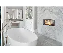 Foyer au gaz linéaire double face Canyon 35, créant une ambiance de spa de luxe dans une salle de bain avec un mur en marbre et un bain autoportant.