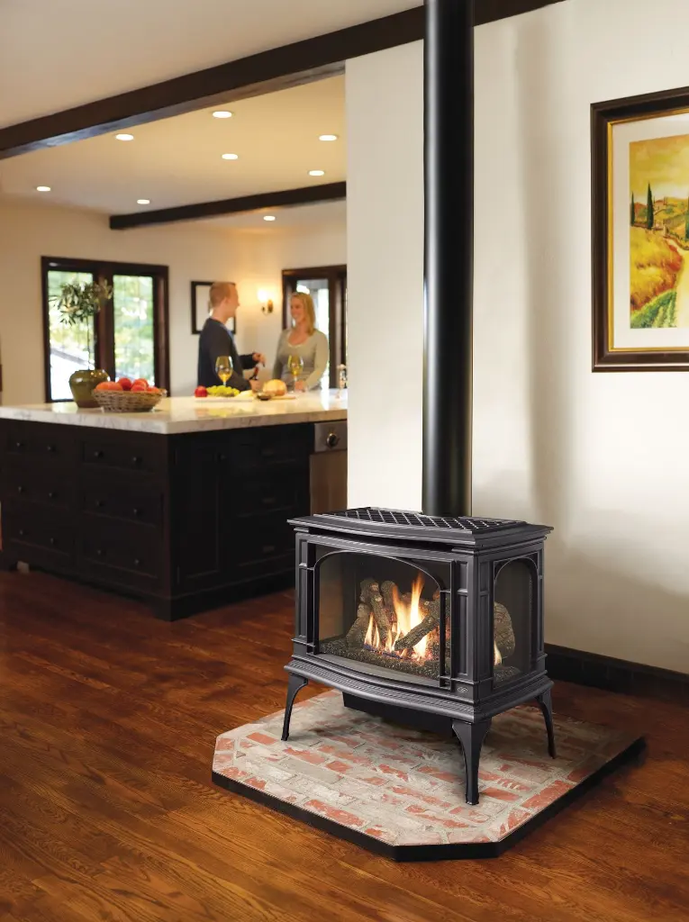 Poêle à gaz Greenfield de Lopi avec vue sur trois côtés, servant de séparateur de pièce chaleureux entre une cuisine et un salon.