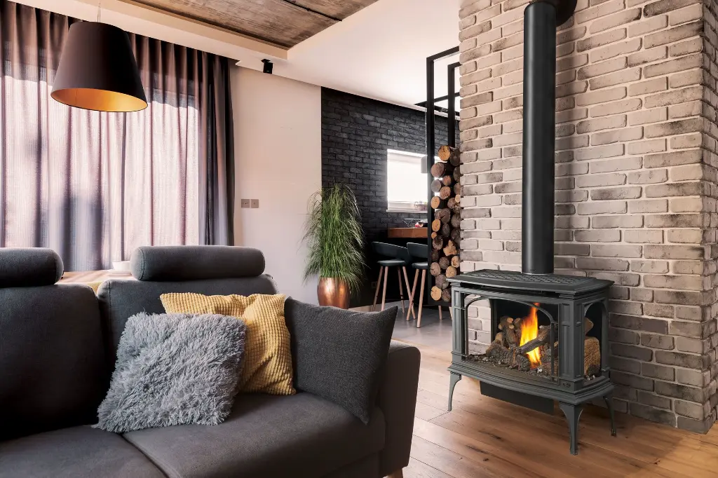 Style industriel avec le grand poêle à gaz Greenfield de Lopi, créant un point focal devant un mur de briques peintes en noir.