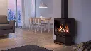 Poêle à gaz Optima 45 d'Archgard, offrant une vue sur trois côtés et un entretien facile grâce à sa vitre sur pentures, dans un décor scandinave moderne.