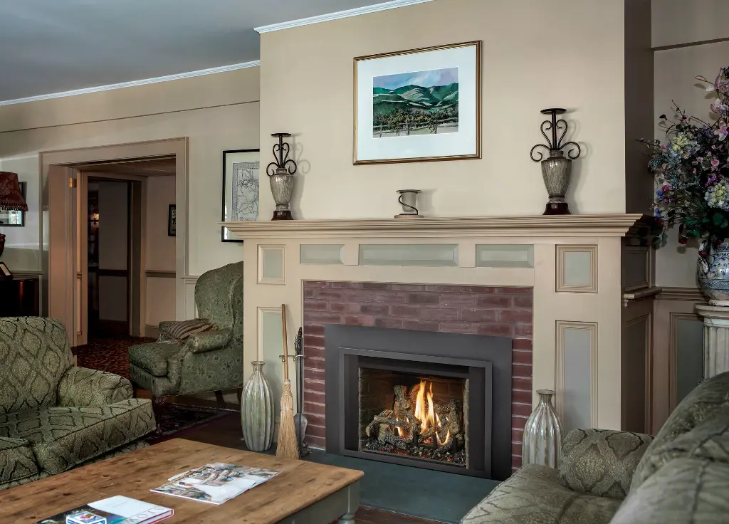 Exemple de rénovation d'un foyer en brique rouge avec l'insert au gaz 34 DVL de FireplaceXtrordinair et un manteau de foyer blanc de style traditionnel.