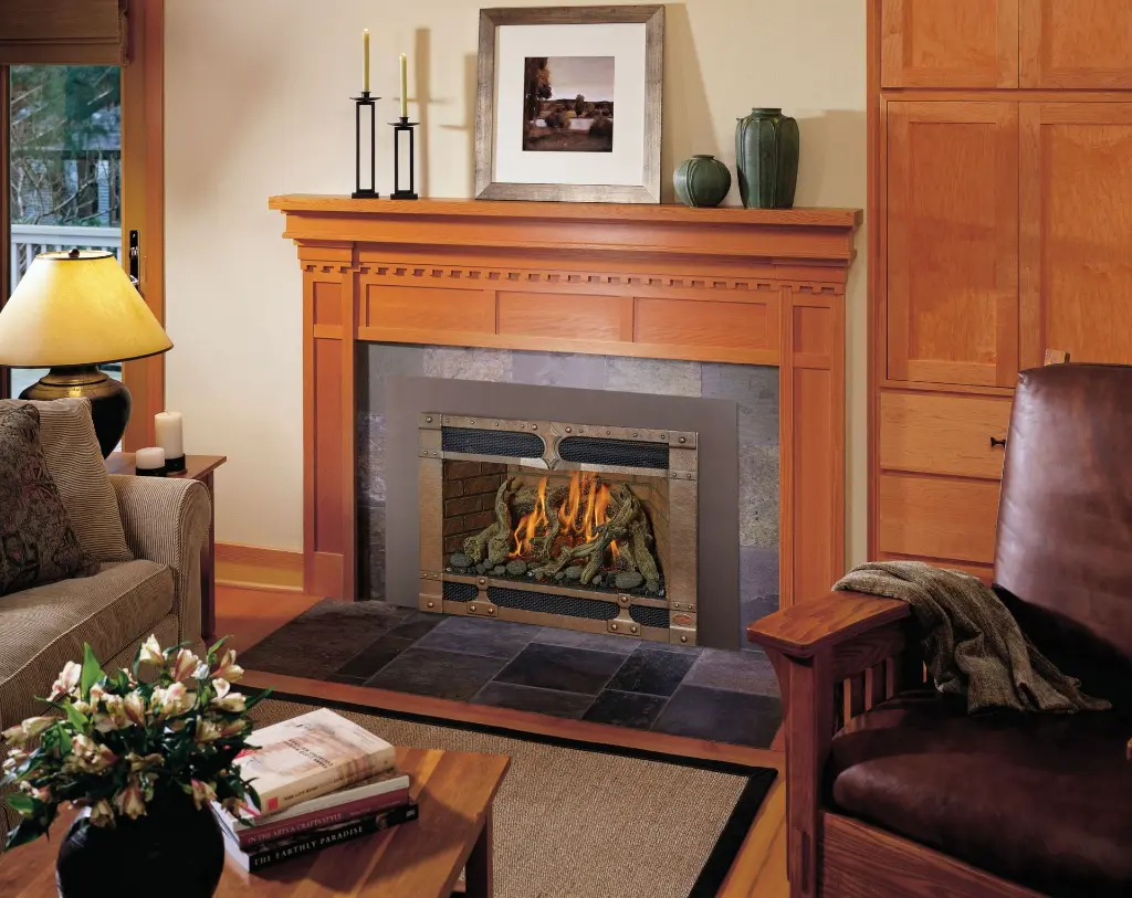 Insert au gaz 34 DVL de FireplaceXtrordinair avec une façade décorative de style artisanal, complétant un manteau de foyer en bois de chêne.