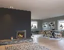 Insert au gaz Jotul GI 535 avec façade arquée en acier, créant un point focal dans un salon au design scandinave moderne avec un âtre en pierre.